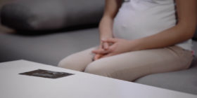 Schwangere Frau neben Ultraschallbild