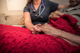 Krankenschwester hält die Hand einer Palliativpatientin.